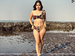 Urfi Javed in a floral one-shoulder bikini on a rocky shoreline HD wallpaper