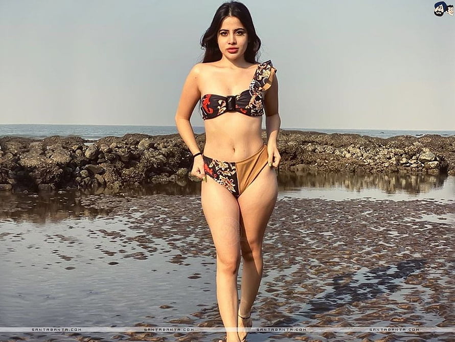 Urfi Javed in a floral one-shoulder bikini on a rocky shoreline HD wallpaper