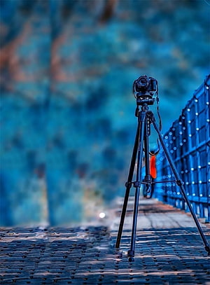 DSLR Camera on Tripod on a Cobblestone Path with Blue Bokeh Background HD phone wallpaper