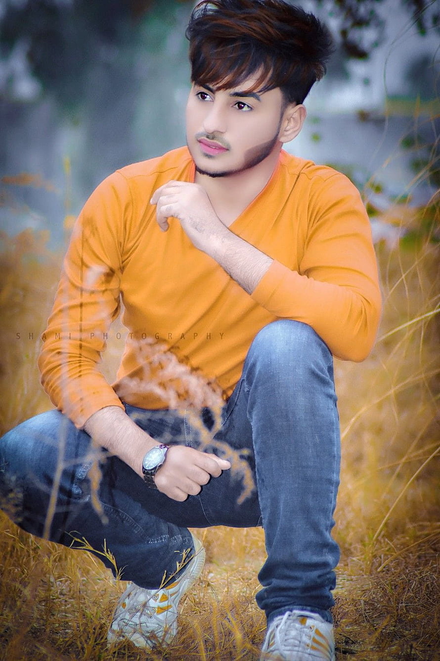 Young man in orange sweater crouching in golden grass with thoughtful pose, Stylish boys Whatsapp DP Profile Pics, whatsapp dp boys HD phone wallpaper