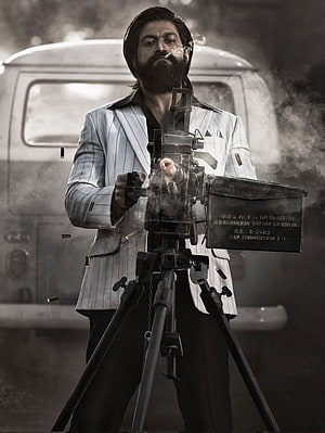 Rocky from KGF Chapter 2 firing a mounted machine gun in a white pinstripe suit HD phone wallpaper