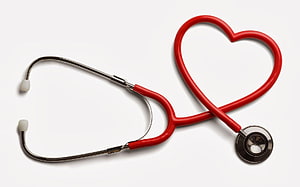 Red stethoscope arranged in a heart shape on a white background HD wallpaper