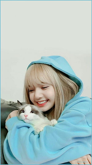 Lisa from BLACKPINK smiling while holding a fluffy Ragdoll cat in a light blue hoodie HD phone wallpaper