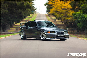 Black BMW M3 E36 Coupe with Widebody Kit and Deep Dish Wheels on a Tree-Lined Road HD wallpaper