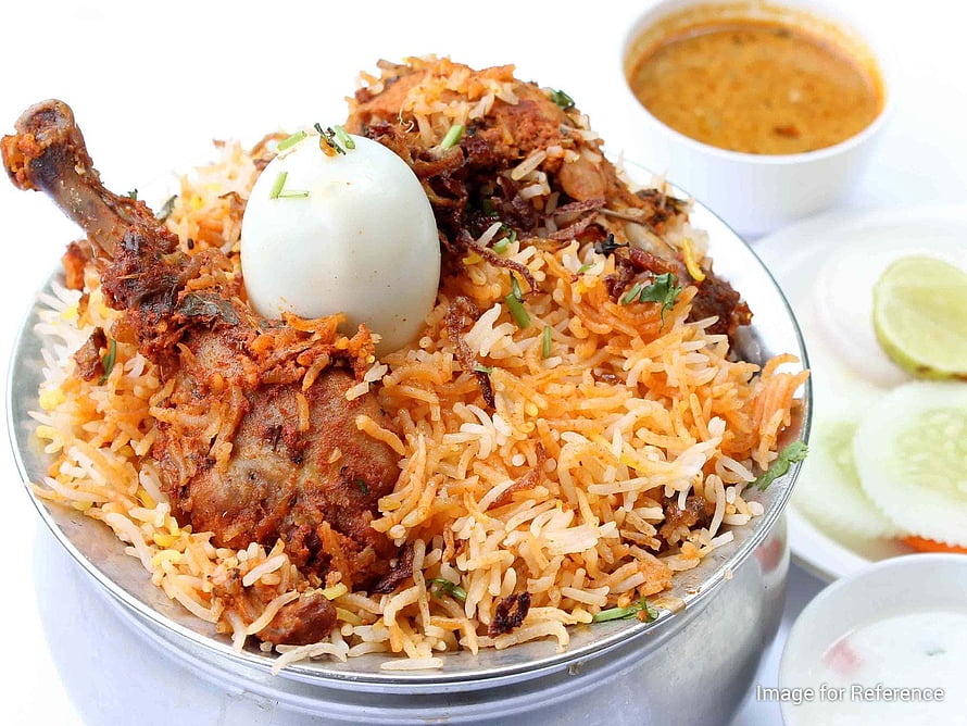 Authentic Chicken Biryani with boiled egg, cucumber slices, and raita served in a traditional metal bowl HD wallpaper