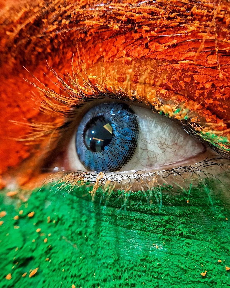 Extreme Close-Up of a Blue Eye with Vibrant Orange and Green Face Paint HD phone wallpaper