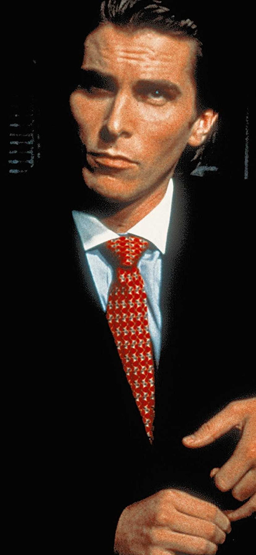 Patrick Bateman in a dark suit with a red patterned tie against a black background HD phone wallpaper