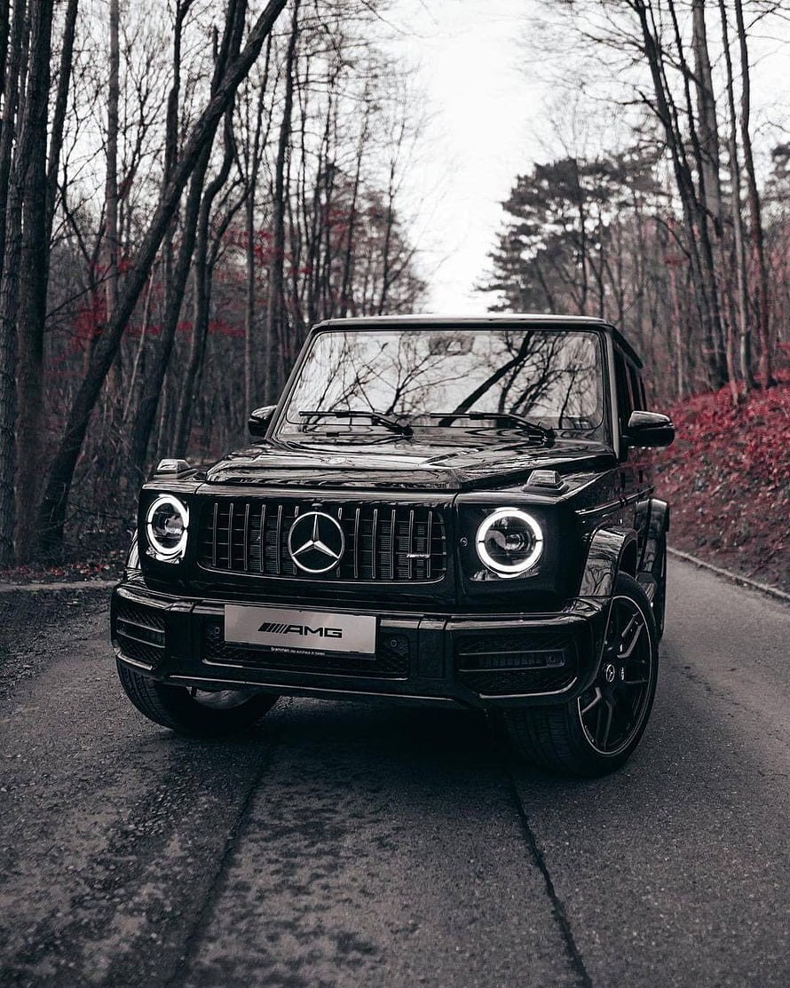 Black Mercedes-Benz G-Class AMG parked on a forest road with circular LED headlights HD phone wallpaper