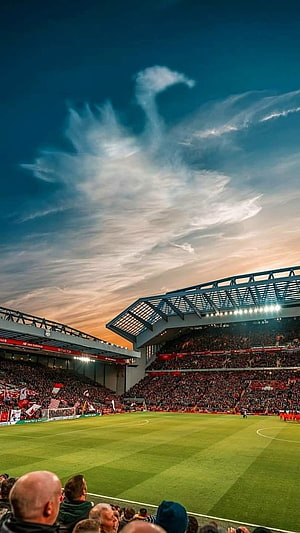 Anfield Stadium at Sunset with Dramatic Clouds Over the Pitch HD phone wallpaper