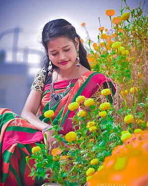 Young woman in a vibrant pink and green sari sitting among blooming marigold flowers, santali girl HD phone wallpaper