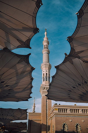 Grand Mosque Minaret Framed by Decorative Canopies Under a Clear Blue Sky HD phone wallpaper