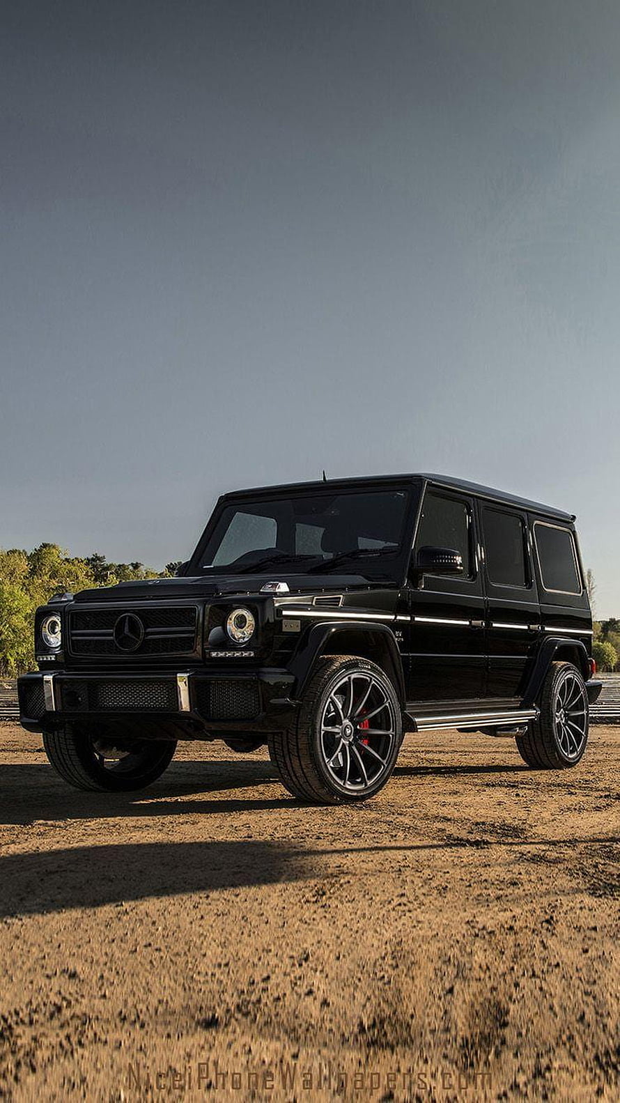 Black Mercedes-AMG G63 SUV on a dirt road under a clear sky HD phone wallpaper