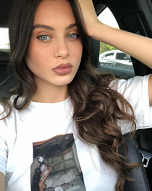 Lana Rhoades in a white graphic tee with long wavy hair, seated inside a car HD phone wallpaper