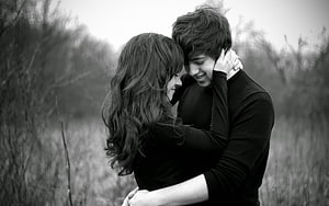 Black and White Portrait of a Young Couple Embracing in a Natural Setting HD wallpaper