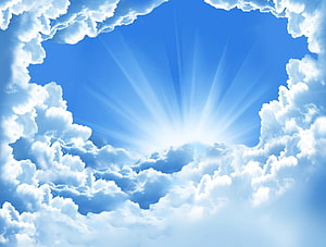 Sunburst Rays Breaking Through Fluffy White Clouds in a Bright Blue Sky HD wallpaper