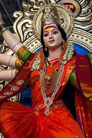 Ornate Durga Bhavani Devi Statue in Vibrant Red Saree with Gold Jewelry and Floral Garland HD phone wallpaper