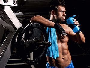 Muscular Man Resting With Blue Shaker Bottle And Gym Towel In Dark Fitness Studio HD wallpaper
