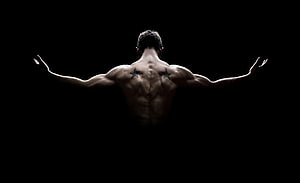 Muscular Male Back View with Star Tattoos and Arms Outstretched Against Black Background HD wallpaper
