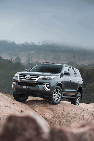 2015 Toyota Fortuner SUV on Rocky Hillside with Misty Mountain Landscape HD phone wallpaper