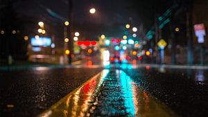 Rain-soaked city street at night with colorful bokeh lights reflecting on wet asphalt HD wallpaper