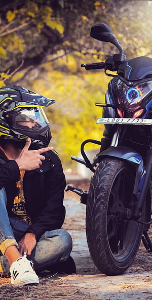 Biker Crouching Beside Pulsar NS 200 Motorcycle on a Forest Trail HD phone wallpaper