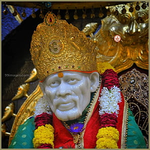Sai Baba of Shirdi statue adorned with a golden crown and vibrant flower garlands HD phone wallpaper