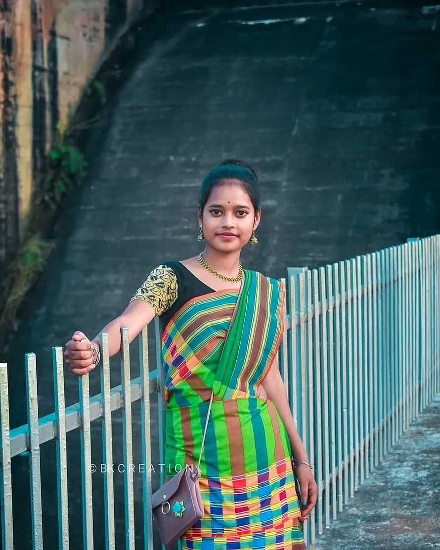 Young woman in colorful striped sari standing by a metal railing HD phone wallpaper