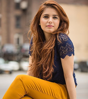 Portrait of a woman with long auburn hair wearing a navy lace top and mustard pants HD phone wallpaper