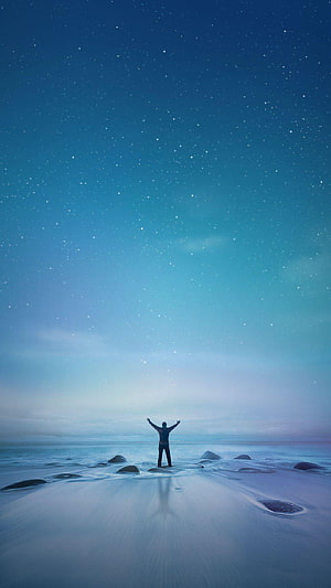 Silhouette of a Person with Raised Arms on a Starry Night Beach HD phone wallpaper