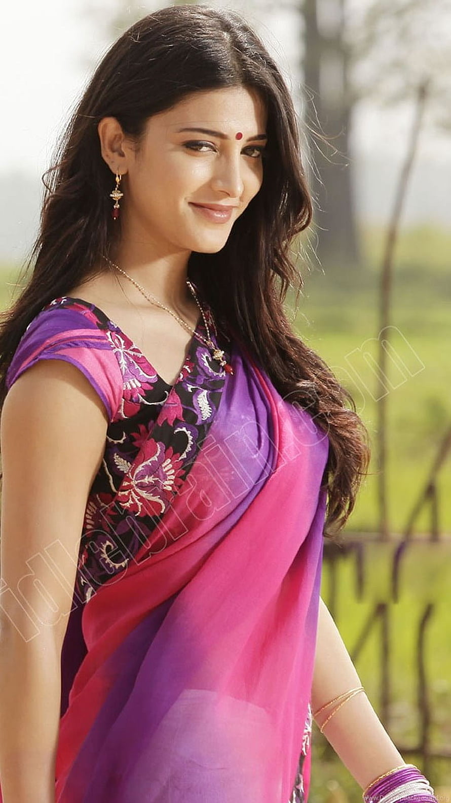 Shruthi Hassan in a vibrant purple and pink floral saree with traditional gold jewelry HD phone wallpaper