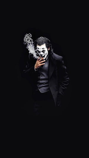 Black Joker in a dark suit smoking a cigarette with dramatic smoke against a black background HD phone wallpaper