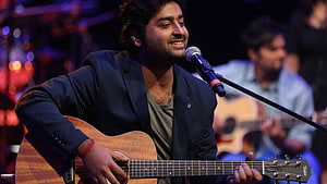 Arijit Singh performing live on stage with acoustic guitar and microphone HD wallpaper