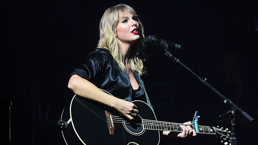 Taylor Swift performing live on stage with acoustic guitar and microphone HD wallpaper