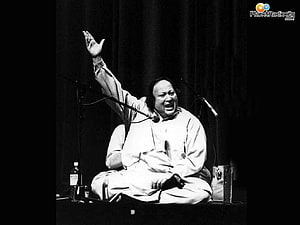 Nusrat Fateh Ali Khan performing Qawwali with raised hand on stage in black and white HD wallpaper