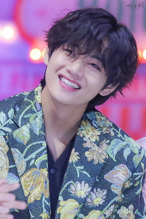 Kim Taehyung smiling in a floral blazer against a vibrant purple stage backdrop HD phone wallpaper