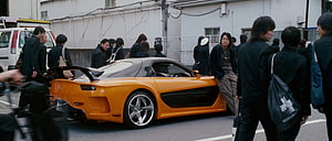 Orange Mazda RX-7 Supercar Parked on Urban Street with Crowd of Onlookers HD wallpaper