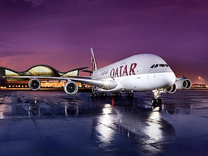 Qatar Airways Airbus A350 on wet tarmac at dusk with illuminated terminal in background HD wallpaper