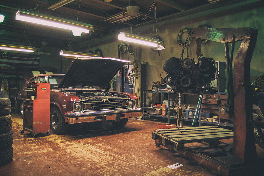 Vintage Muscle Car Under Repair in a Classic Auto Workshop with Engine Hoist HD wallpaper