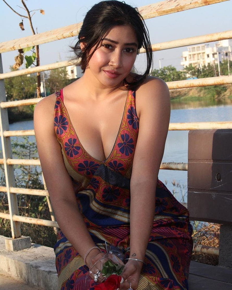 Sofia Ansari in a floral patterned dress holding a red rose by a riverside railing HD phone wallpaper