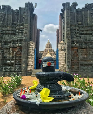 Shivling with flower offerings at an ancient Indian temple complex HD phone wallpaper