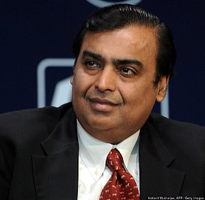 Mukesh Ambani in a dark suit and red patterned tie at a formal corporate event HD wallpaper