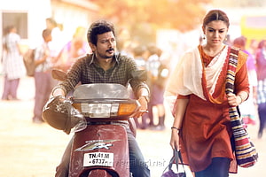 Manithan Movie Still: Man on Scooter and Woman in Traditional Attire Walking Through a Crowded Street HD wallpaper