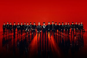 NCT 2020 and NCT 127 members in black stage outfits against a vivid red backdrop HD wallpaper