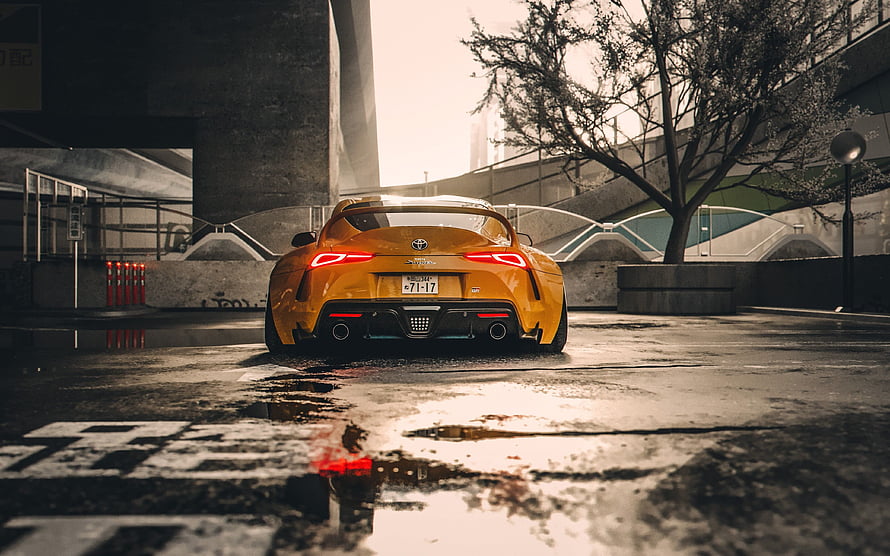 Rear View of a Yellow Toyota Supra Parked on a Wet Urban Street in Tokyo HD wallpaper