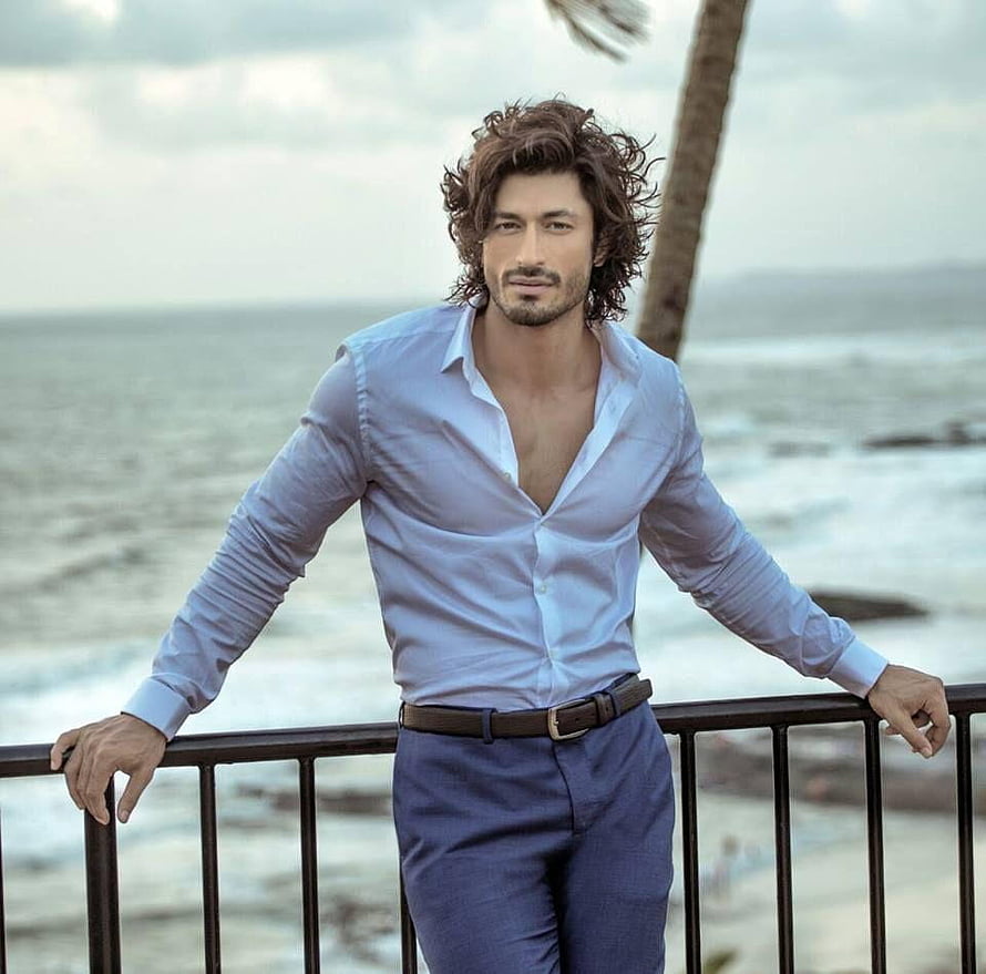 Vidyut Jammwal in a light blue shirt and navy trousers leaning on a seaside railing HD wallpaper