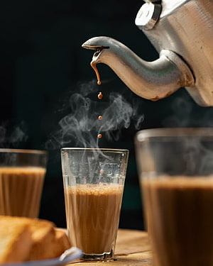 Steaming Chai Poured from a Metal Kettle into a Glass Cup HD phone wallpaper