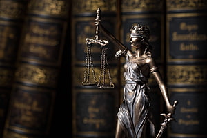 Bronze Statue of Themis Holding Scales and Sword in Front of Law Books HD wallpaper