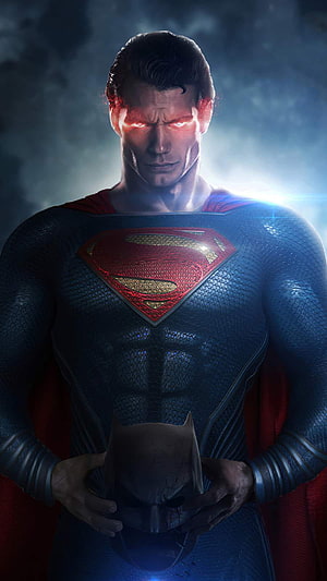 Superman Holding Cracked Batman Mask with Glowing Red Eyes in Dark Cinematic Scene HD phone wallpaper