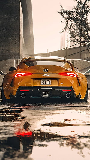 Rear View of a Golden Toyota Supra Parked on a Wet Urban Street HD phone wallpaper
