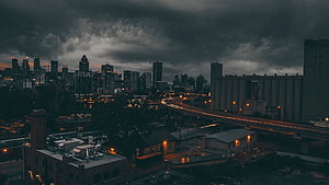 Moody Urban Skyline at Dusk with Dramatic Storm Clouds and City Lights HD wallpaper